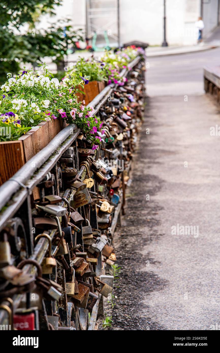 Un primo piano di un ponte romantico adornato da fiori colorati e numerose serrature d'amore, che simboleggiano l'amore eterno. Foto Stock