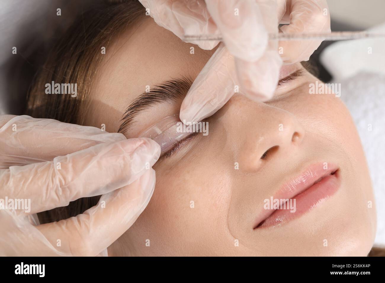 Procedura di laminazione delle ciglia. Estetista che posiziona il cuscinetto in silicone sulla palpebra della donna nel salone di bellezza, primo piano Foto Stock