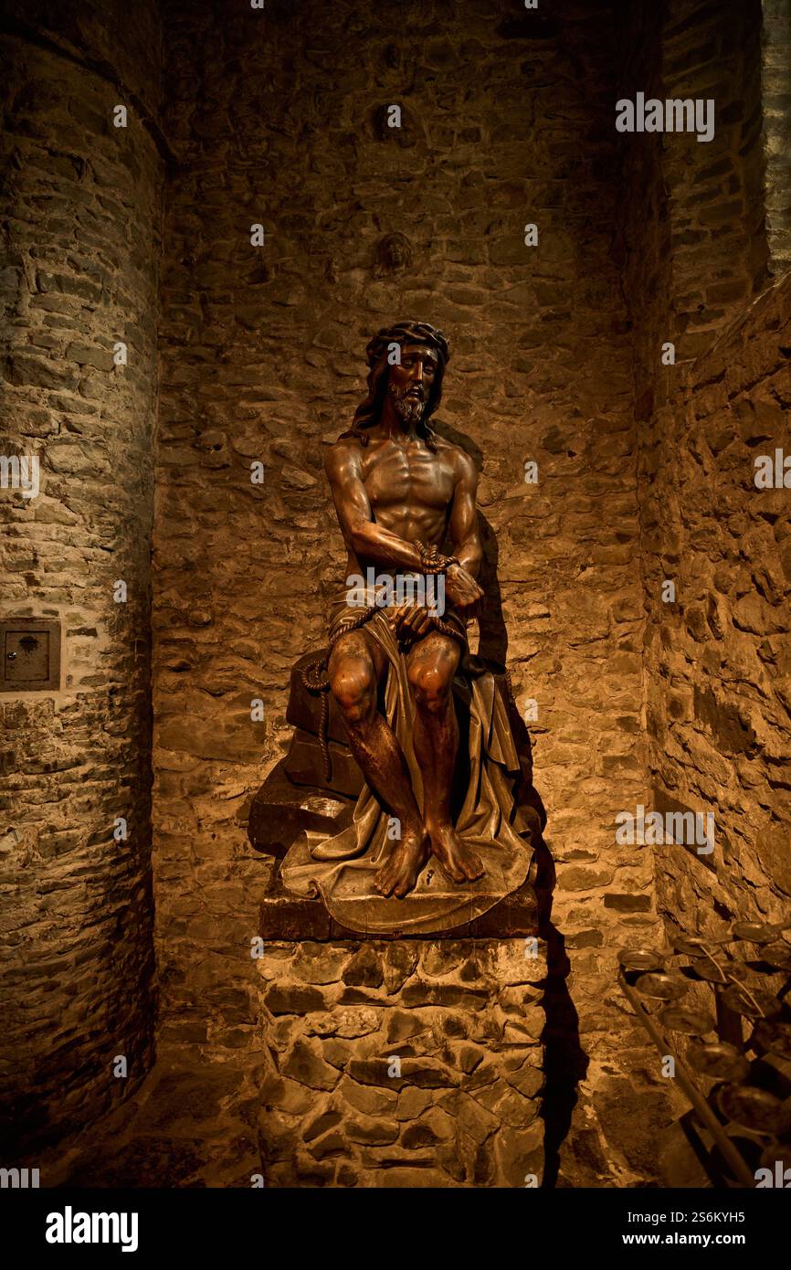 Statua in bronzo di gesù cristo seduta con mani legate in nicchia di pietra. Turismo belga Foto Stock