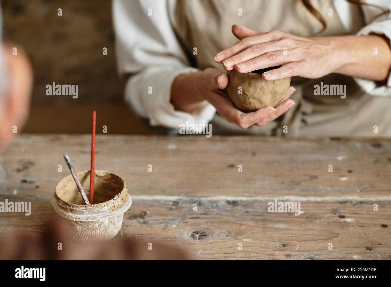 la donna forma l'argilla in una lezione di ceramica, godendosi del tempo di qualità. Foto Stock