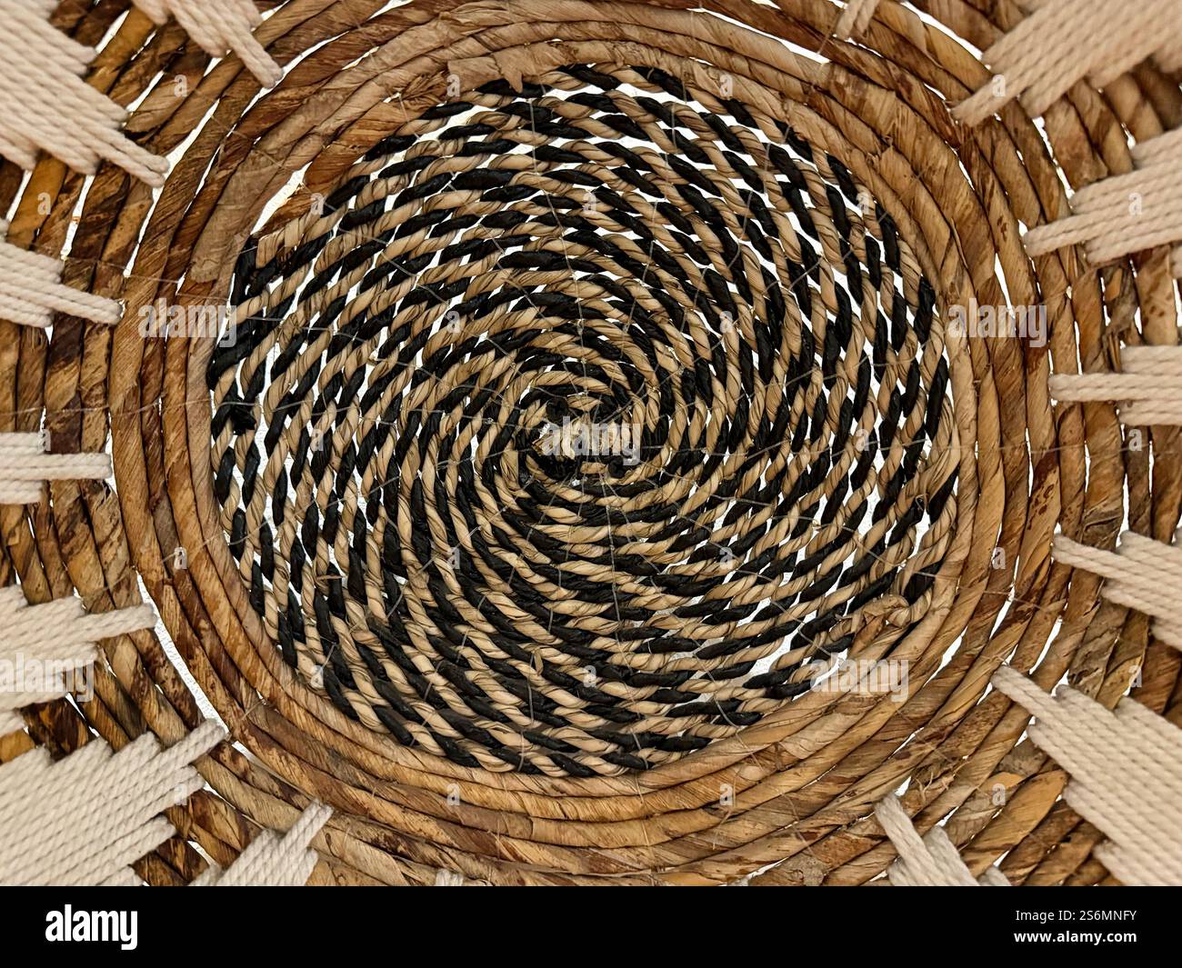 Arte e artigianato a spirale casuale in rattan o vimini, cesto in rattan sintetico rotondo a spirale o decorazione a parete. Foto Stock