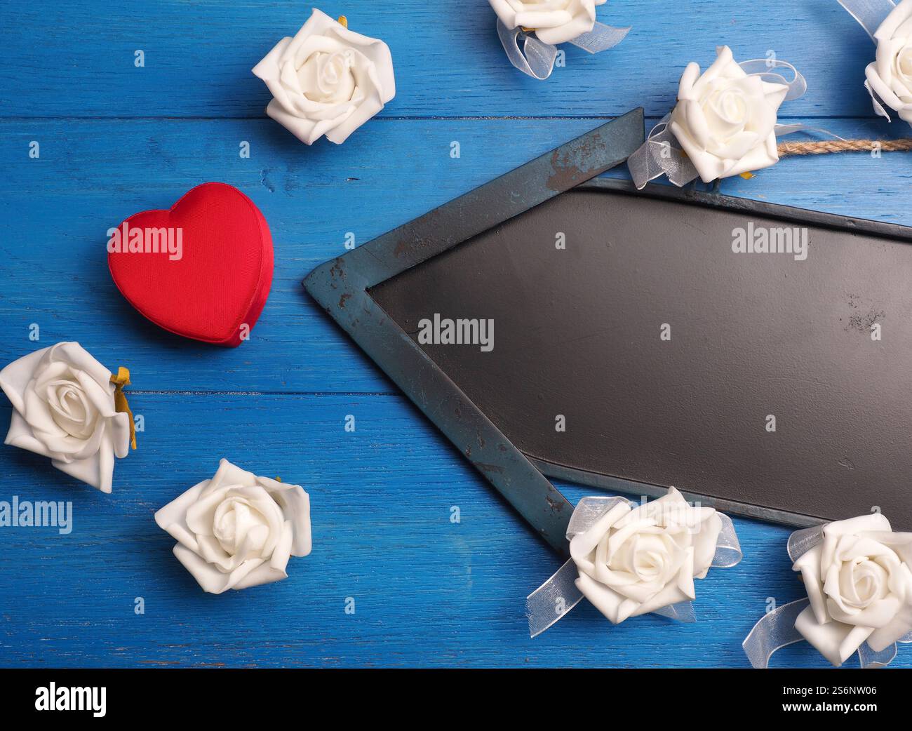 Cuore rosso a forma di scatola regalo con una lavagna freccia su un pavimento in legno Foto Stock