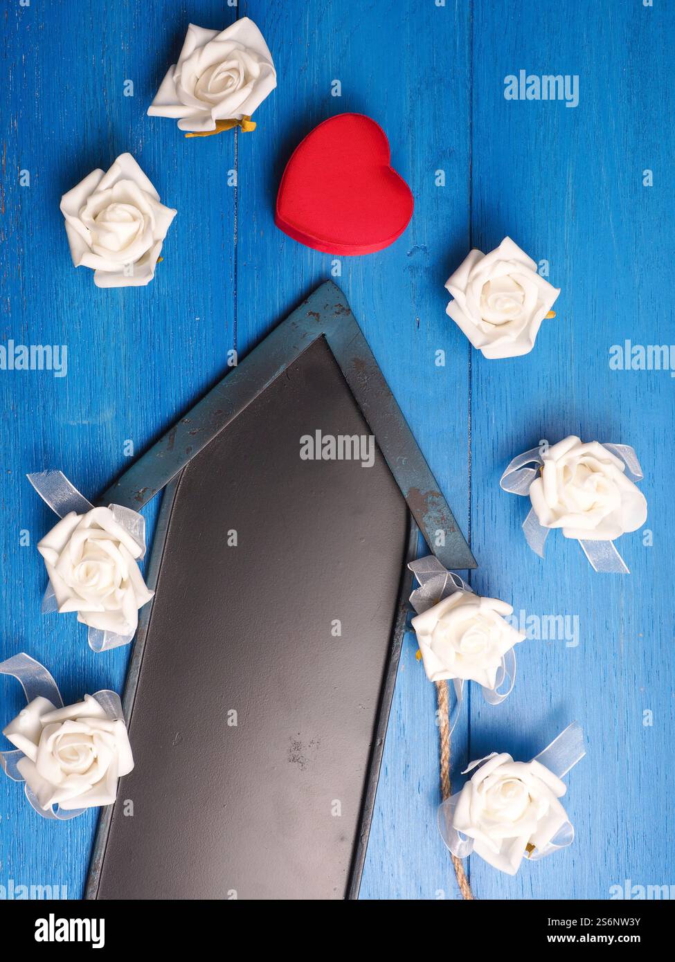 Cuore rosso a forma di scatola regalo con una lavagna freccia su un pavimento in legno Foto Stock