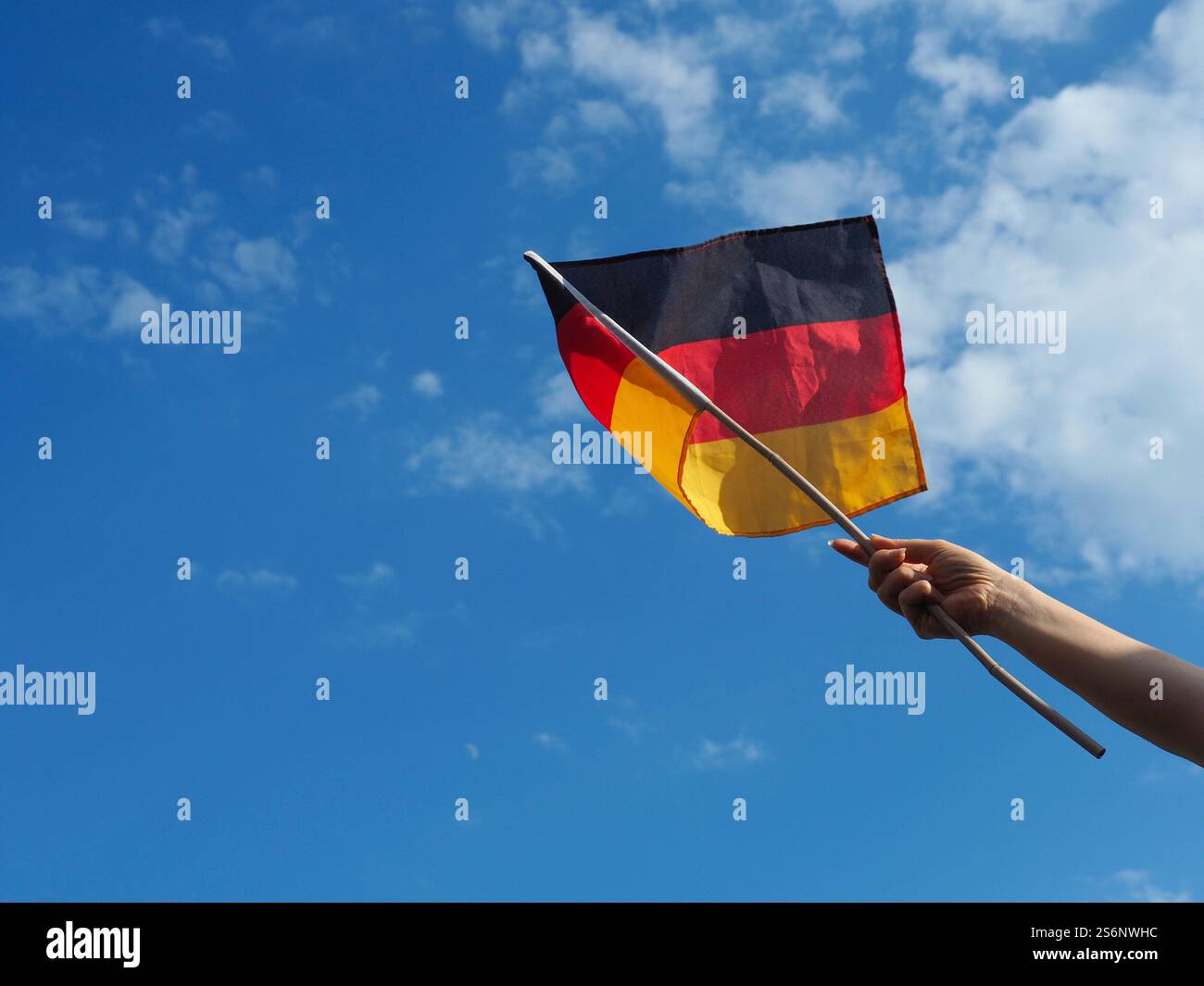 Femmina lato sventola una bandiera tedesca su un Cielo di estate blu Foto Stock