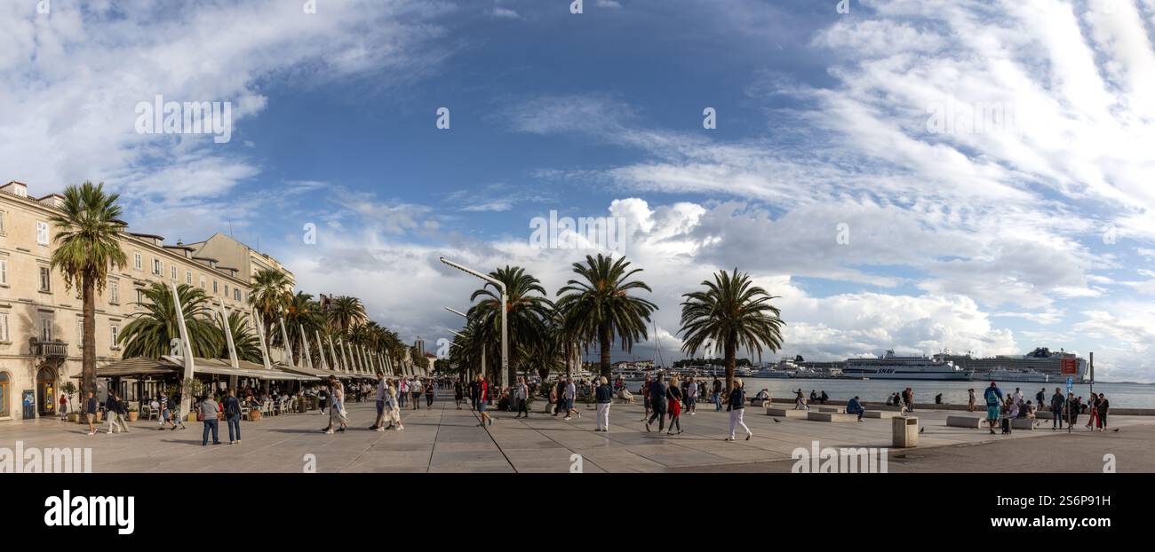 Panorámica del paseo Marítimo de Split, Riva, con sus palmeras y cafés, lleno de vida con Tourist que disfrutan del ambiente costero. Croacia Foto Stock