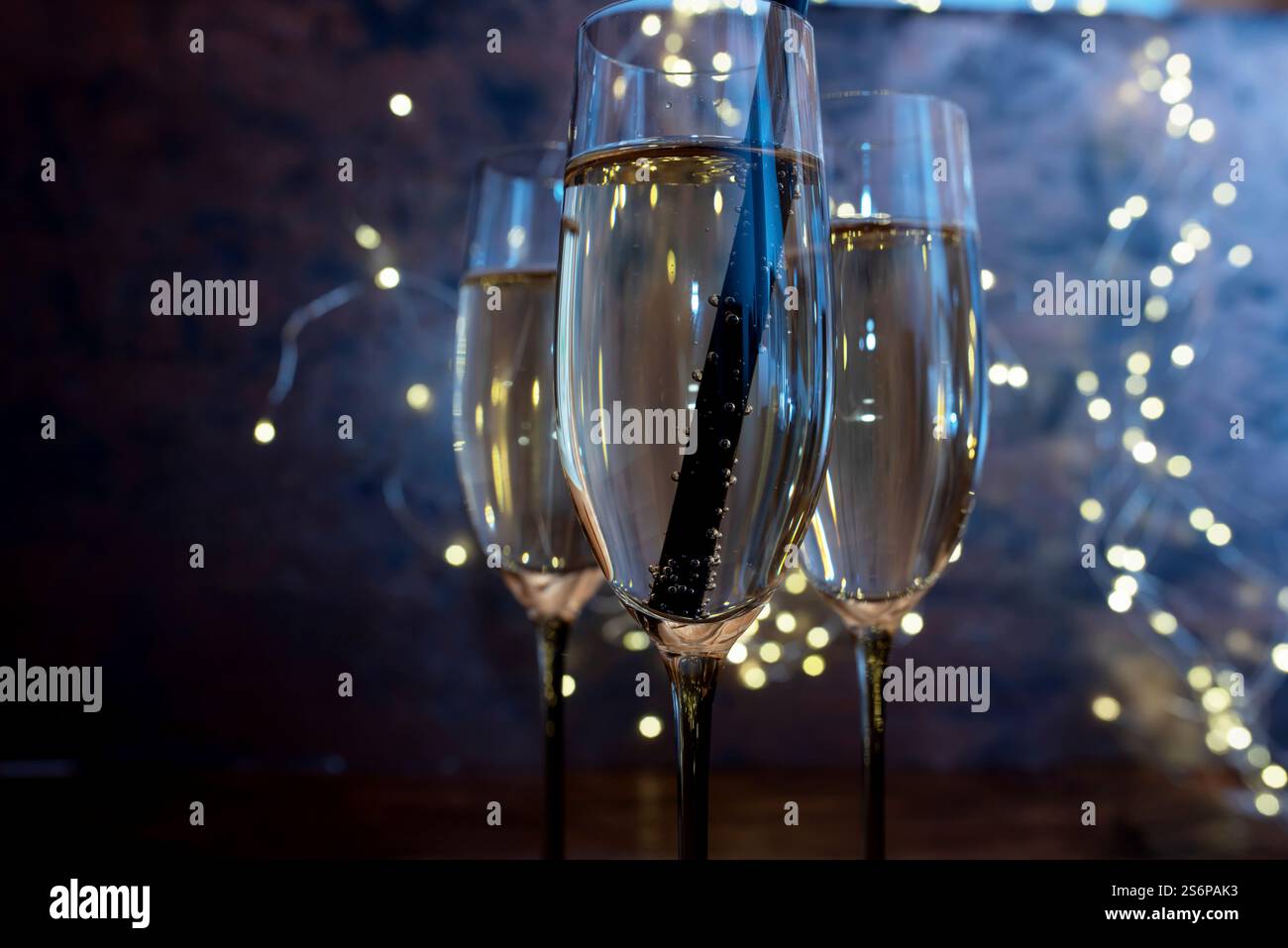 Bicchieri con champagne di luce blu e bokeh festivo. Suggestivo sfondo di Capodanno per momenti festivi e spazio per il testo. Primo piano. Foto Stock