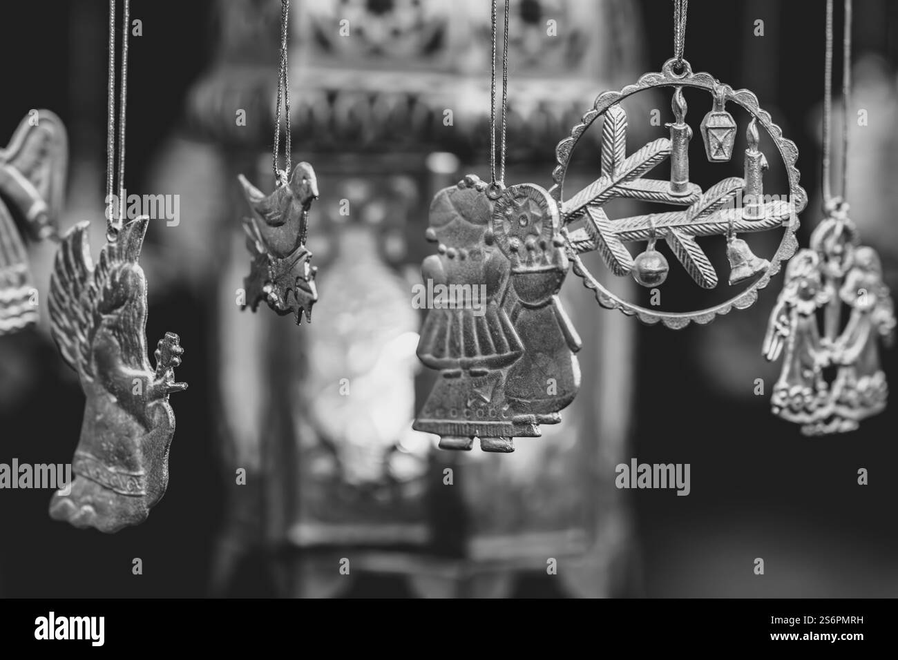 Una collezione di ornamenti in argento appesi a un apparecchio di illuminazione. Gli ornamenti includono angeli, uccelli e altre figure. La scena è tranquilla e serena, a. Foto Stock