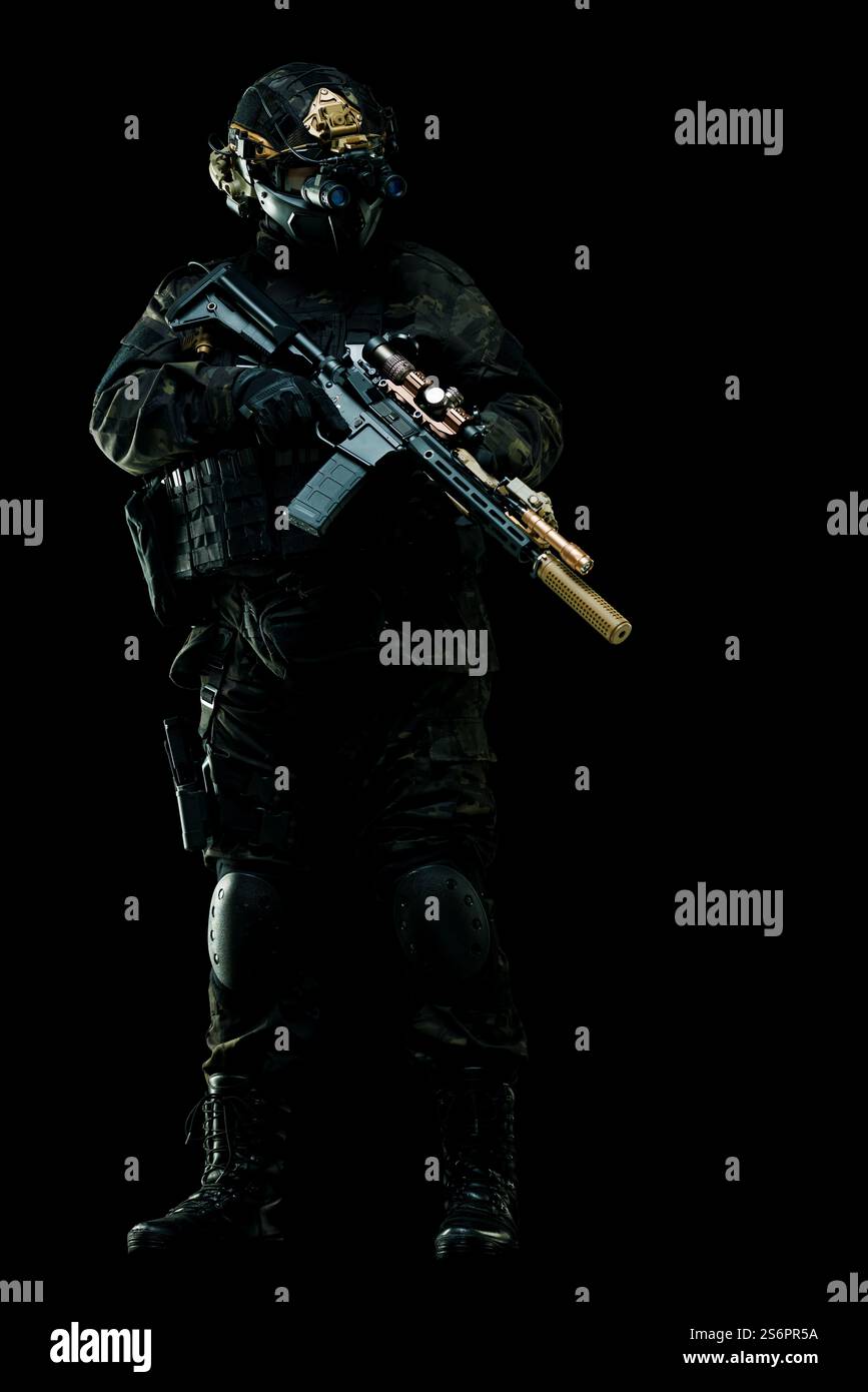 Soldato tattico delle forze speciali che indossa una divisa da combattimento scura, equipaggiato con equipaggiamento e arma su sfondo nero. Mostra disponibilità, sicurezza e mil Foto Stock