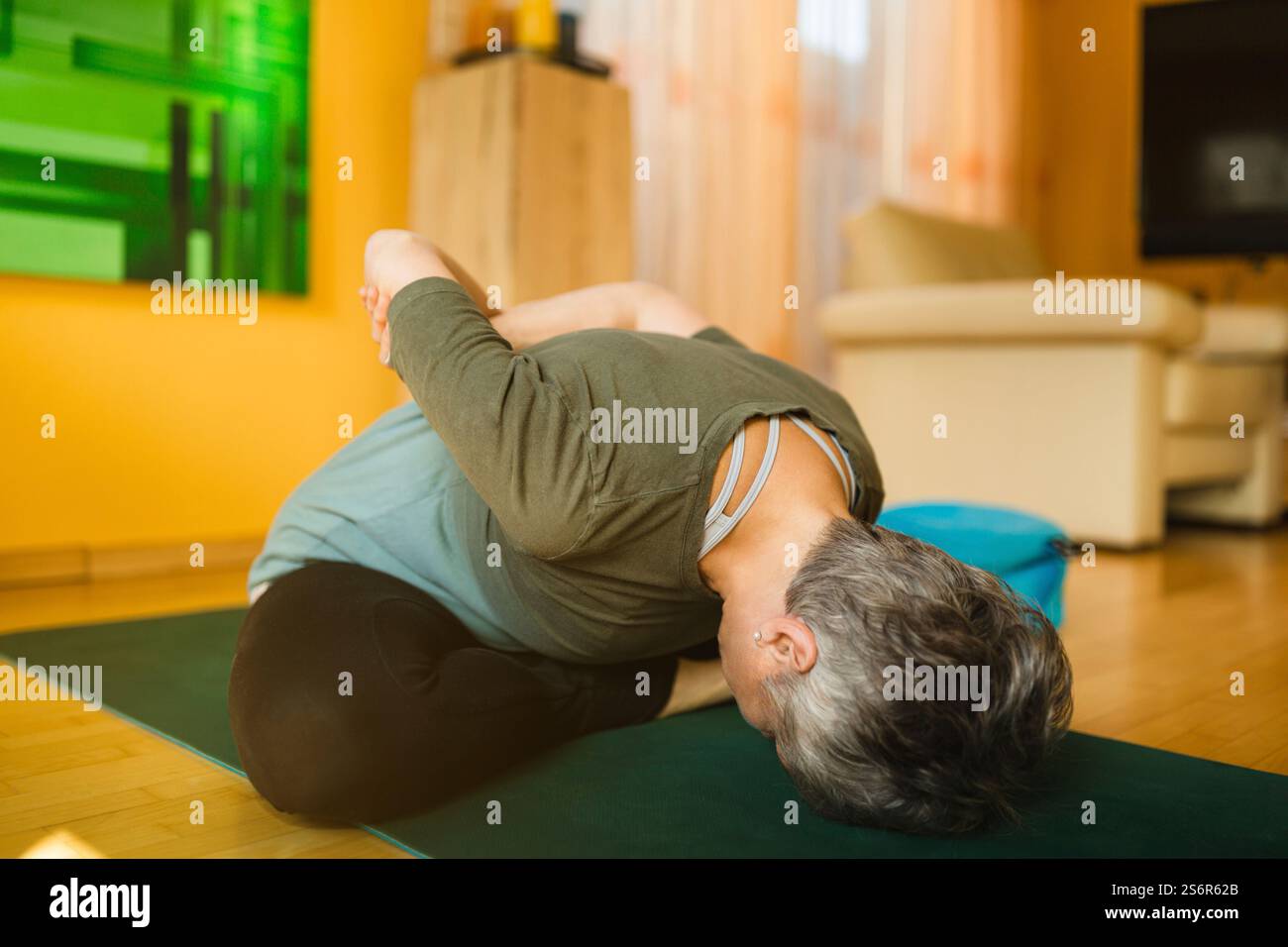 Una donna anziana fa esercizi di yoga a casa Foto Stock