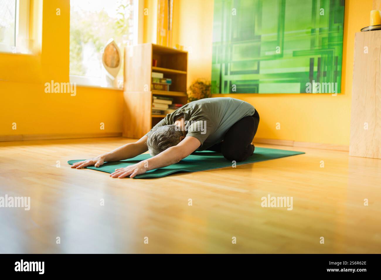 Una donna anziana fa esercizi di yoga a casa Foto Stock