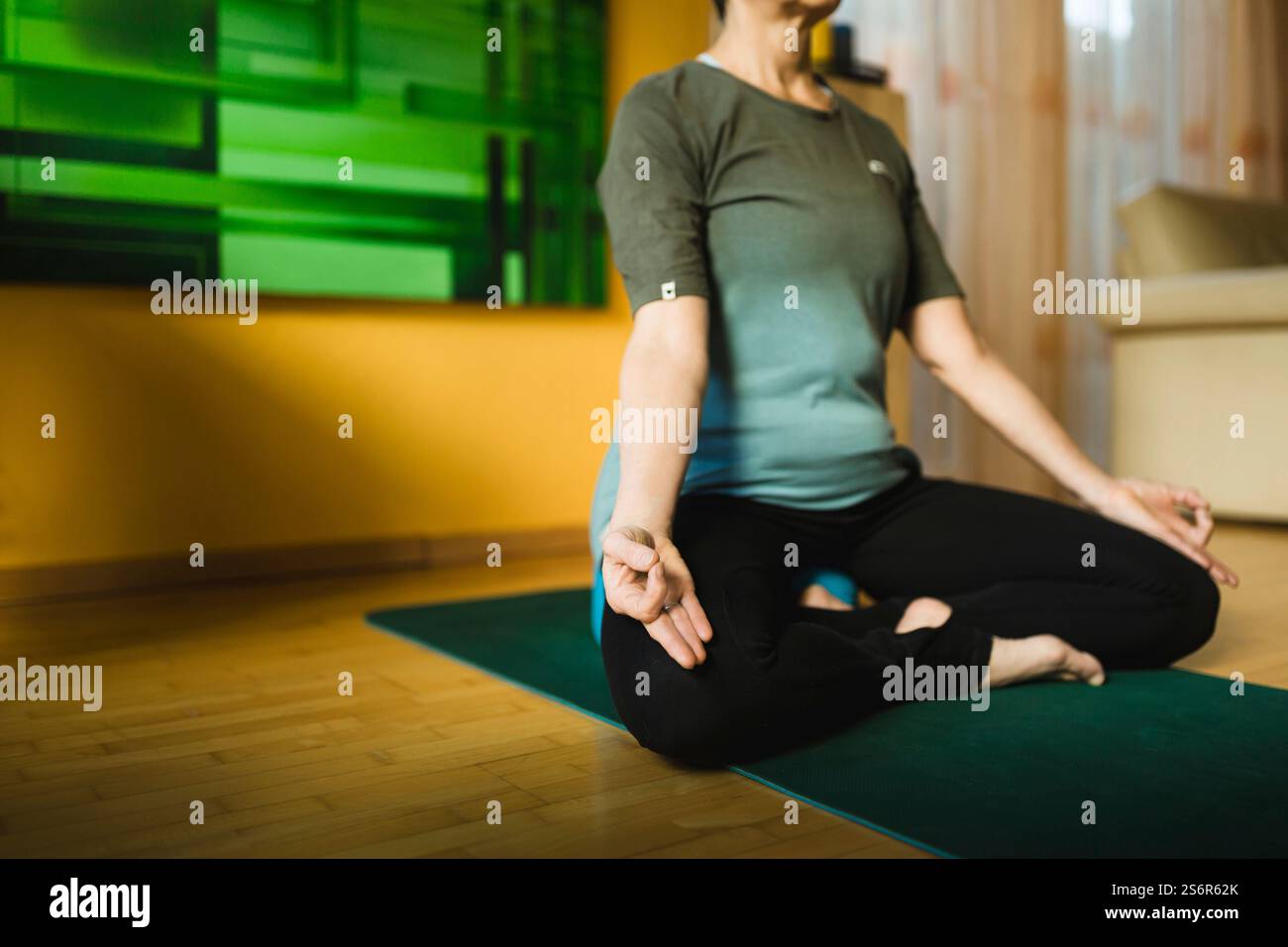 Una donna anziana fa esercizi di yoga a casa Foto Stock