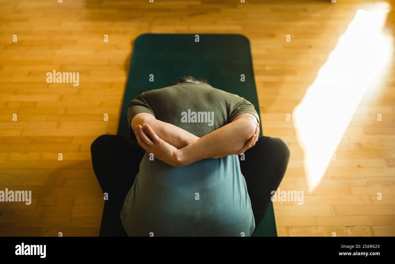 Una donna anziana fa esercizi di yoga a casa Foto Stock
