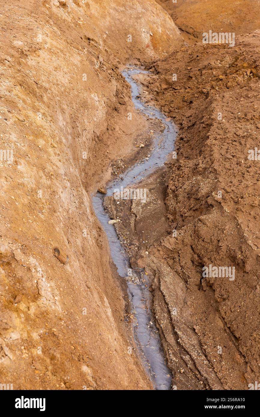 Torrente di fango grigio caldo in una fessura di suolo solforico arancione a Hverir, area geotermica di Myvatn in Islanda Foto Stock