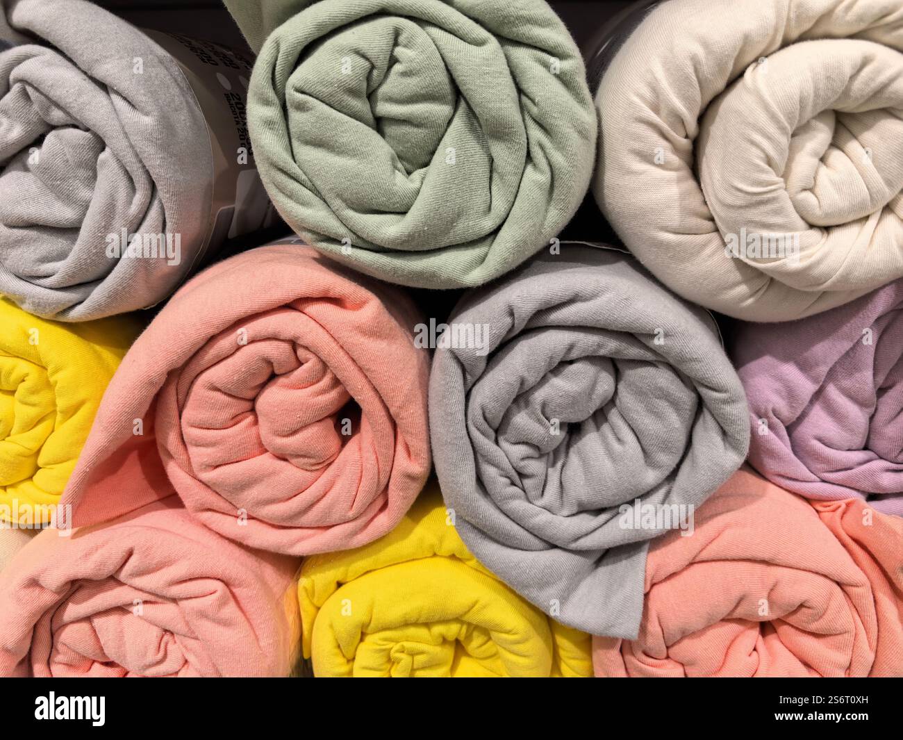 Le morbide coperte in tonalità pastello sono elegantemente disposte in rotoli, a mostrare le loro invitanti texture e colori. Perfetto per aggiungere comfort e calore Foto Stock