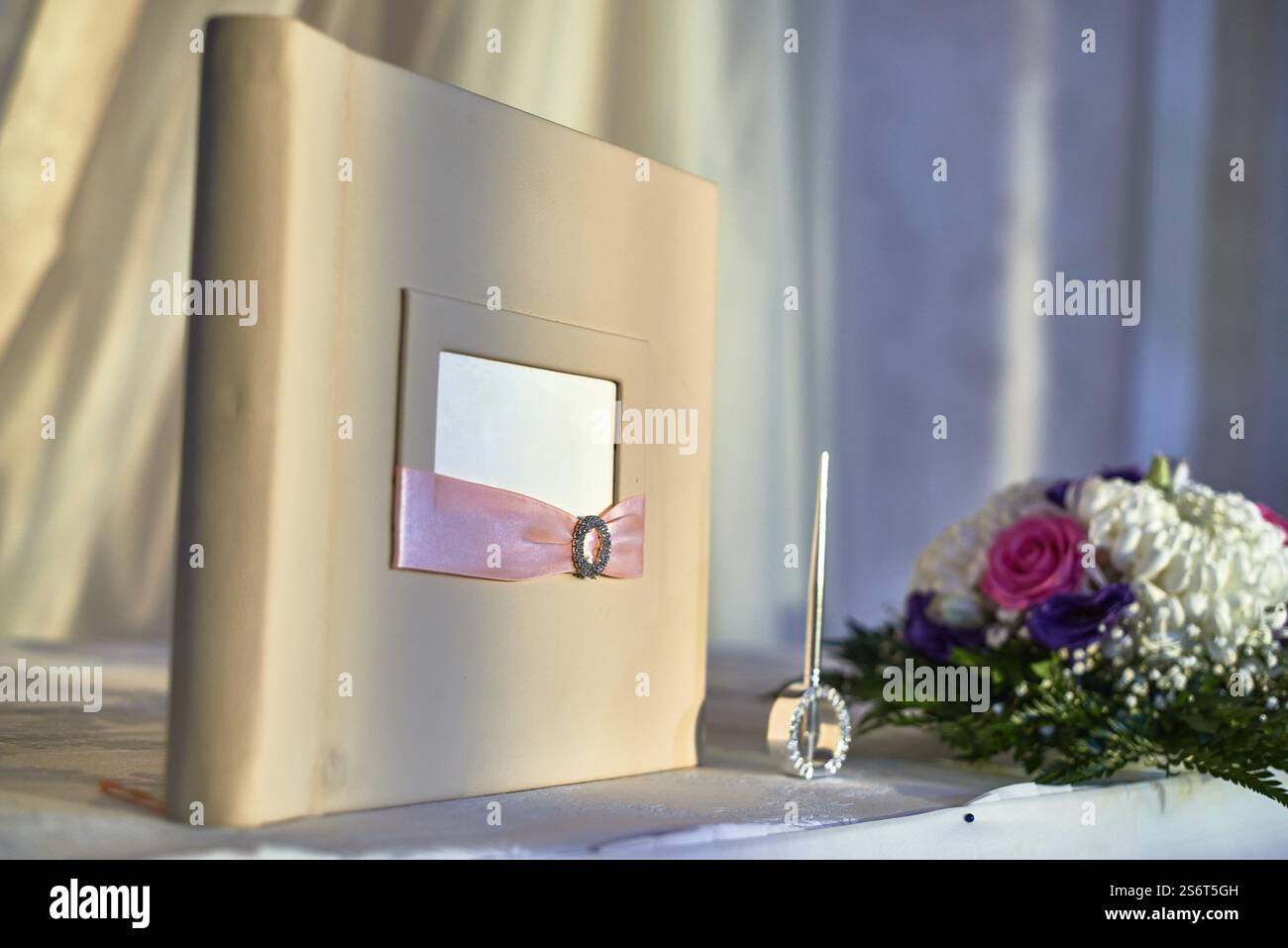 Libro per gli ospiti di nozze elegantemente posizionato sul tavolo con penna e bouquet, simboleggiando il concetto di unione, evento, amore e celebrazione Foto Stock