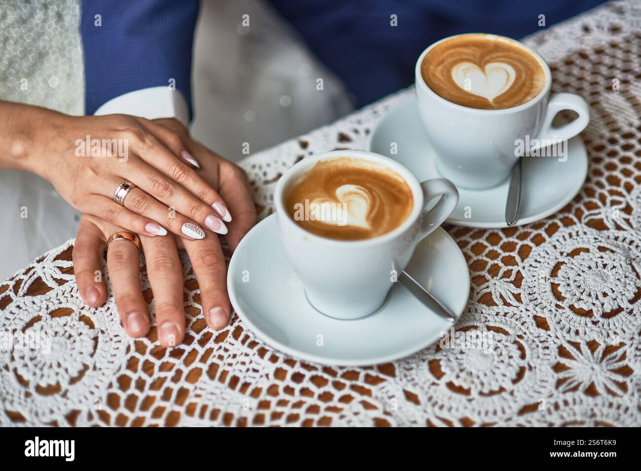 Elegante immagine del giorno delle nozze delle mani degli sposi, latte art, tovaglia di pizzo all'uncinetto, romanticismo, due tazze, l'amore di coppia, la forma del cuore, il caffè, l'unità Foto Stock Elegante immagine del giorno delle nozze delle mani degli sposi, latte art, tovaglia di pizzo all'uncinetto, romanticismo, due tazze, l'amore di coppia, la forma del cuore, il caffè, l'unità Foto Stock
