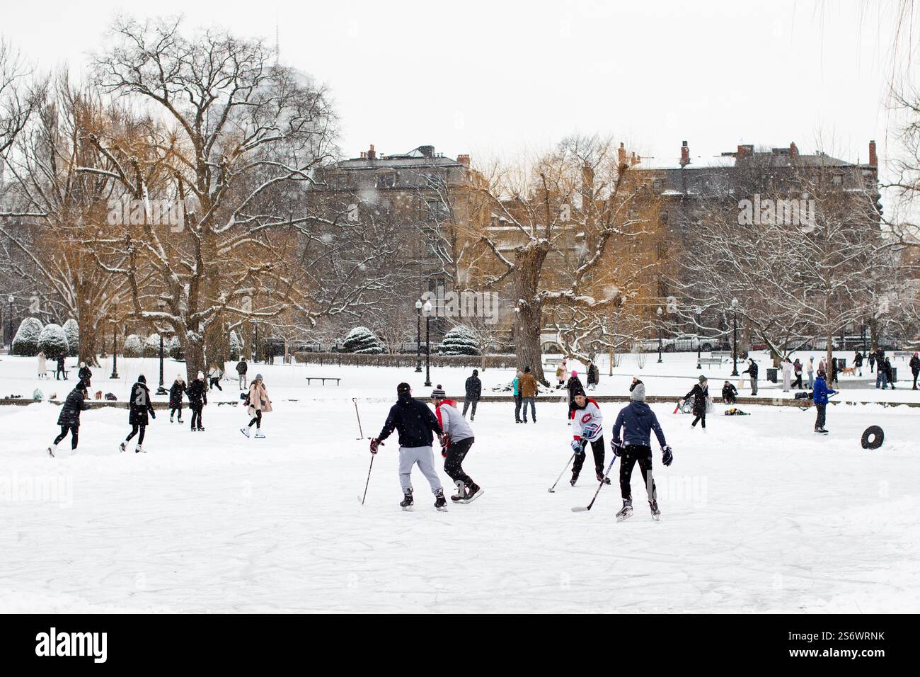 Persone che giocano a hockey e pattinaggio sul ghiaccio sul lago ghiacciato nel giardino pubblico di Boston, Massachusetts, Stati Uniti. Foto Stock