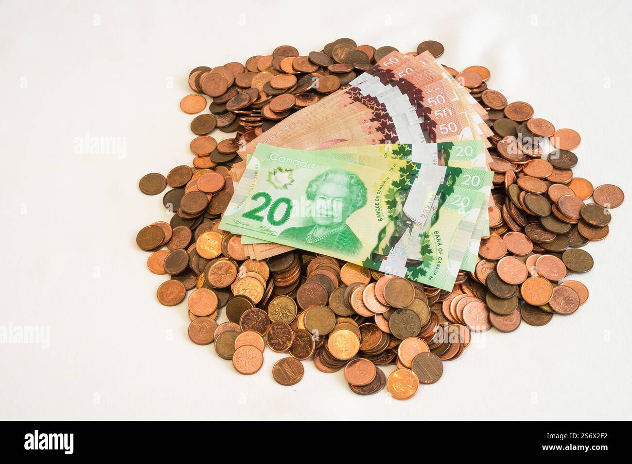 Una pila di monete da un cent fuori produzione coperte da venti e cinquanta banconote Foto Stock