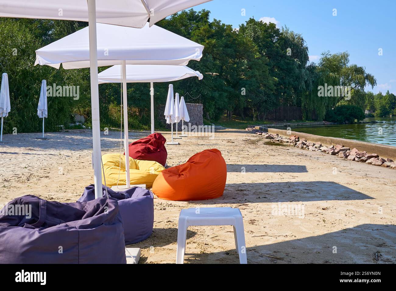 Spiaggia di sabbia deserta e vuota con ombrelloni chiusi vicino al mare e un cane bianco Foto Stock