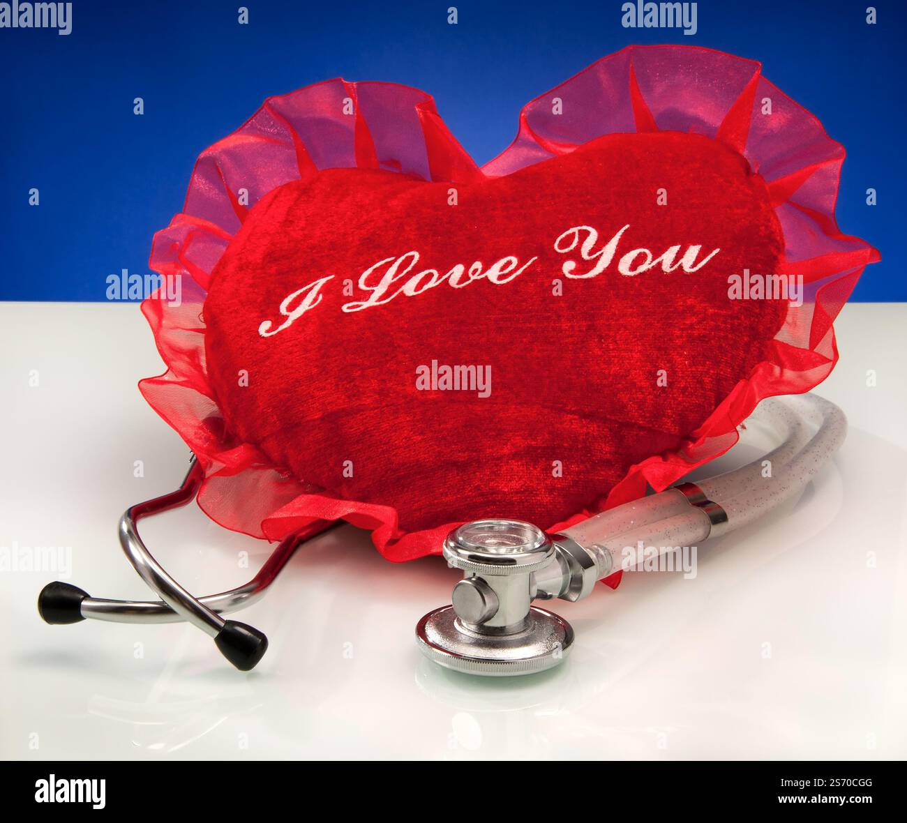 Il cuscino rosso a forma di cuore accanto allo stetoscopio simboleggia l'amore e la consapevolezza della salute del cuore Foto Stock