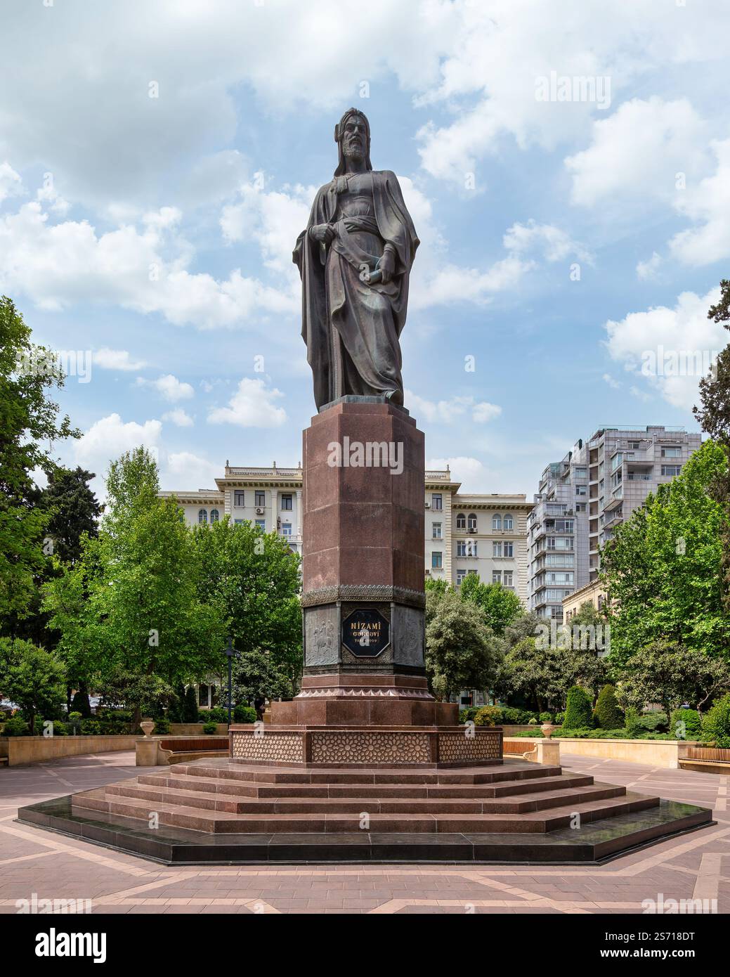Baku, Azerbaigian - 5 maggio 2024: La grande statua di Nizami Ganjavi si trova nel Parco Nizami Ganjavi. Il poeta tiene un libro, che simboleggia il suo contributo alla letteratura persiana, in mezzo a una vegetazione lussureggiante Foto Stock