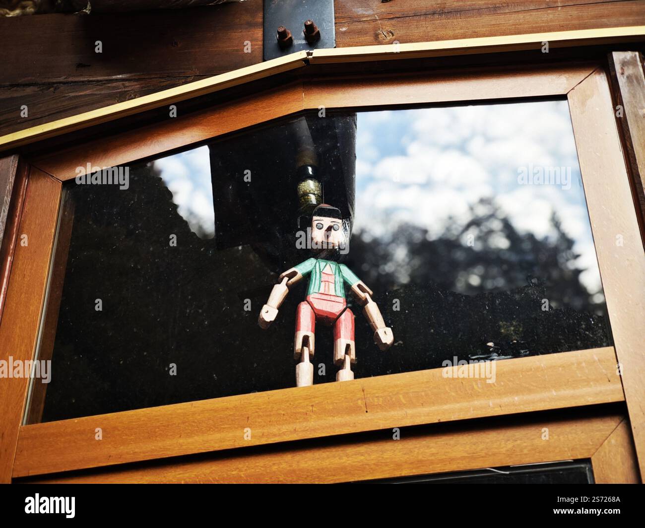 Una decorazione di marionette Pinocchio in legno vintage appesa alla finestra di vetro Foto Stock