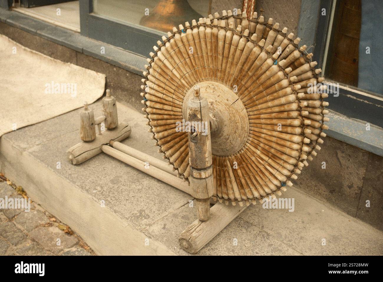 Una ruota da filatura tradizionale in legno vintage utilizzata per filare fibre come lana, cotone e lino in fili tessili Foto Stock