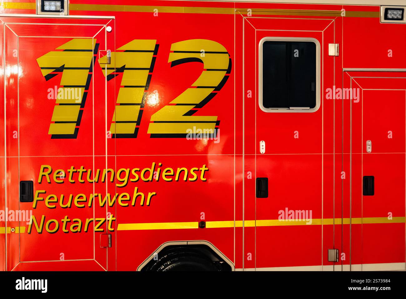 Un'ambulanza rossa e gialla con il numero 112. L'ambulanza è parcheggiata in un garage Foto Stock