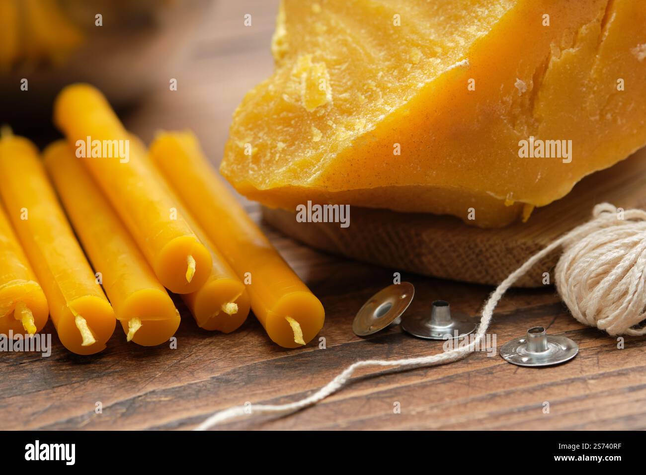 Blocchi di cera d'api naturali, una candela fatta a mano, stoppino e stoppino metallico per creare candele esposte su una superficie rustica in legno. Foto Stock