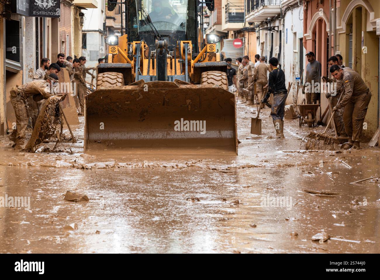 I membri della fanteria e dell'escavatore dell'esercito spagnolo aiutano durante le operazioni di pulizia dopo le inondazioni DANA. La strada è inondata di fango. Paiporta, Spagna Foto Stock