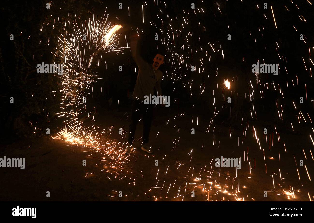 Un palestinese fa esplodere i fuochi d'artificio per festeggiare e rallegrarsi della cessazione della guerra nella Striscia di Gaza e del completamento dell'accordo di scambio di prigionieri tra il governo israeliano e il movimento di resistenza islamica Hamas nella Striscia di Gaza, entrato in vigore questa sera e che tutte le sue fasi sono state rispettate. I palestinesi e gli israeliani si stanno preparando ad accogliere i loro figli, prigionieri e detenuti, detenuti da entrambe le parti. Foto Stock