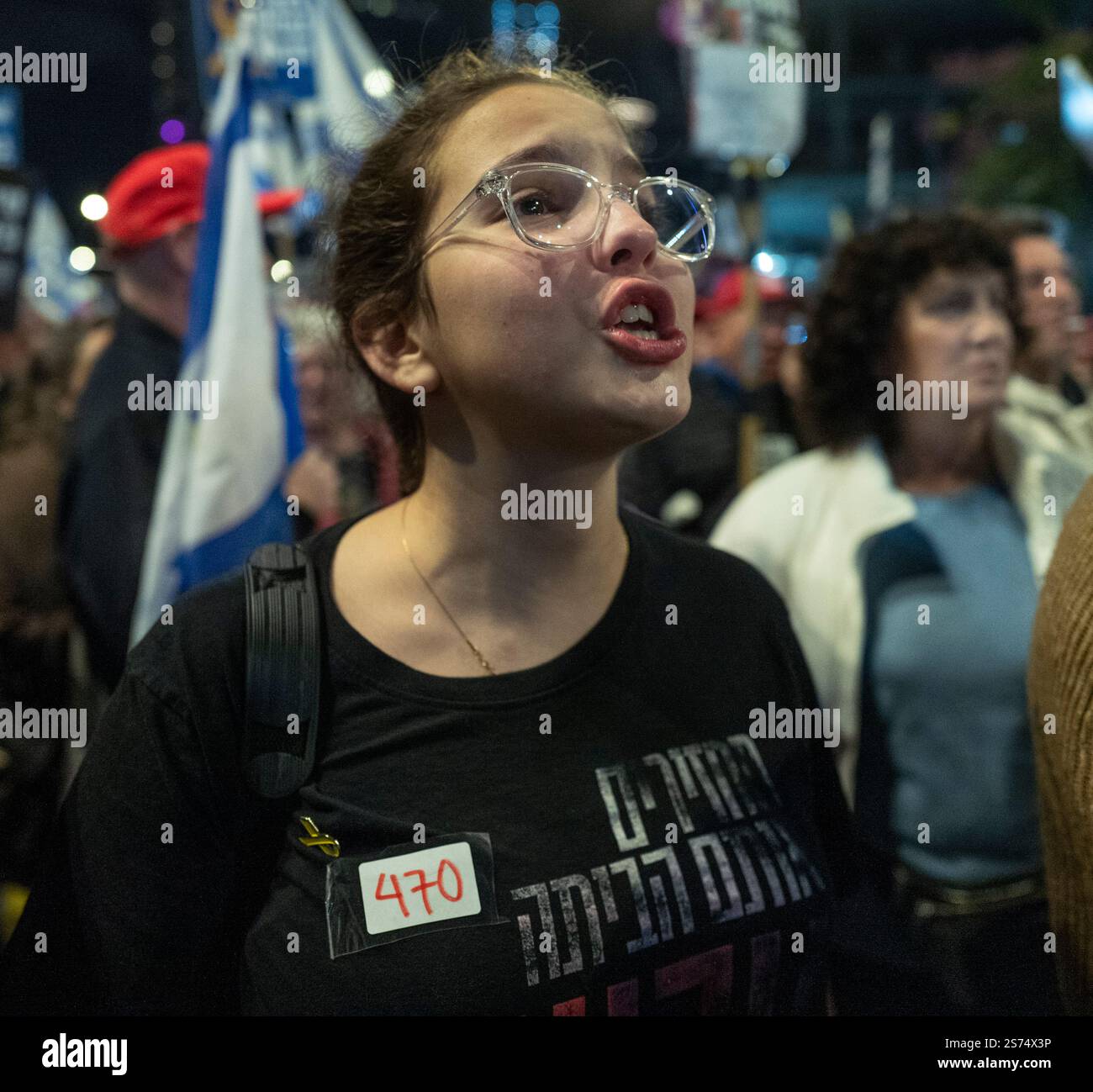 Tel Aviv, Israele. 18 gennaio 2025. Una donna israeliana che ha sollevato per prima e lei e altri urla "ora” mentre i nomi dei 98 ostaggi israeliani vengono letti durante una protesta di massa da migliaia di israeliani che chiedono la fine della guerra e di portare a casa i 98 ostaggi tenuti a Tel Aviv il 18 gennaio 2025 il giorno prima del cessate il fuoco con Hamas, che dovrebbe iniziare domani alle 8. Indossa un cartello con il numero 470 che indica il numero di giorni in cui gli ostaggi sono stati tenuti nella Striscia di Gaza da Hamas, dal loro attacco del 7 ottobre 2023. Foto di Jim Hollander/UPI credito: UPI/Alamy Live News Foto Stock