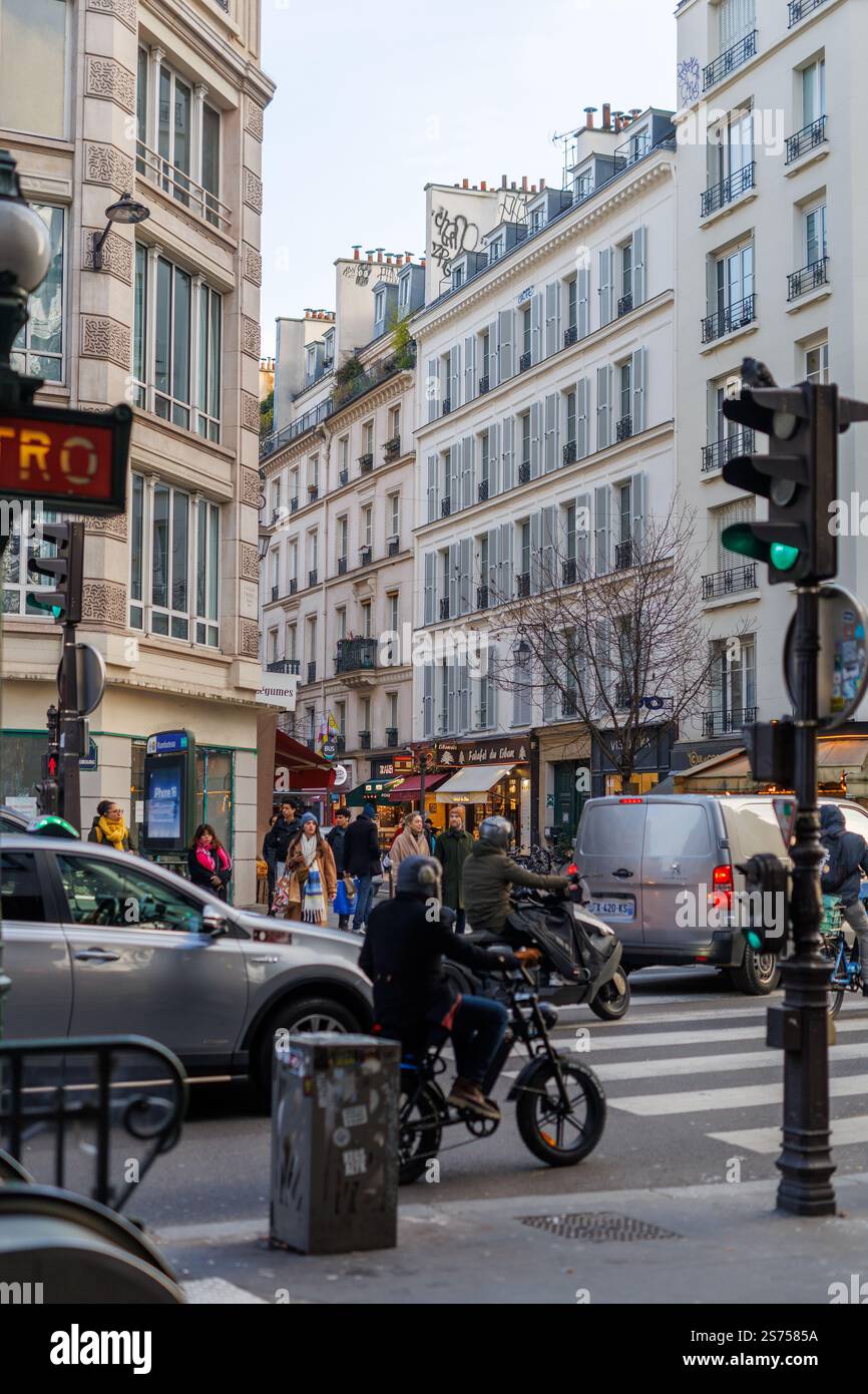 Scena di strada a Parigi con gente, traffico e cartelli della metropolitana, caratterizzata dalla classica architettura parigina e attività vivace a dicembre. Foto Stock