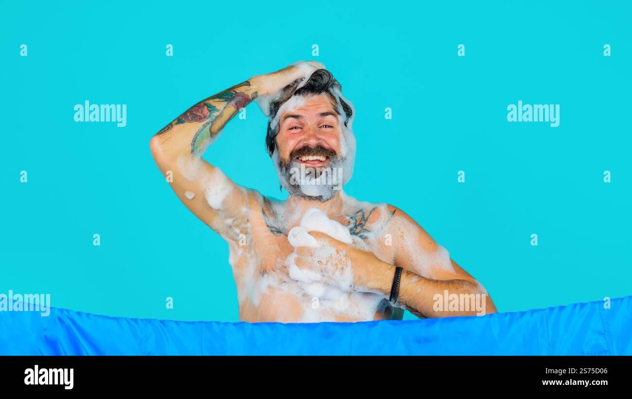Uomo barbuto che fa la doccia, lava il corpo e la testa. Cura della pelle, cura del corpo e spa. Uomo sorridente che fa la doccia con gel idratante e spugna di sapone. Gli uomini co Foto Stock