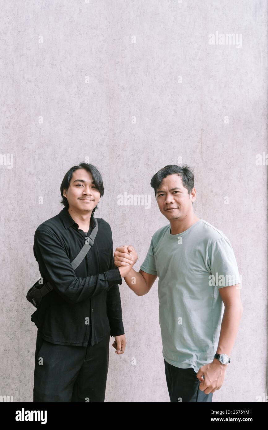 Due uomini stringono la mano dopo aver raggiunto un accordo relativo ai contenuti su un telefono cellulare, simboleggiando il successo della comunicazione e della collaborazione. Foto Stock