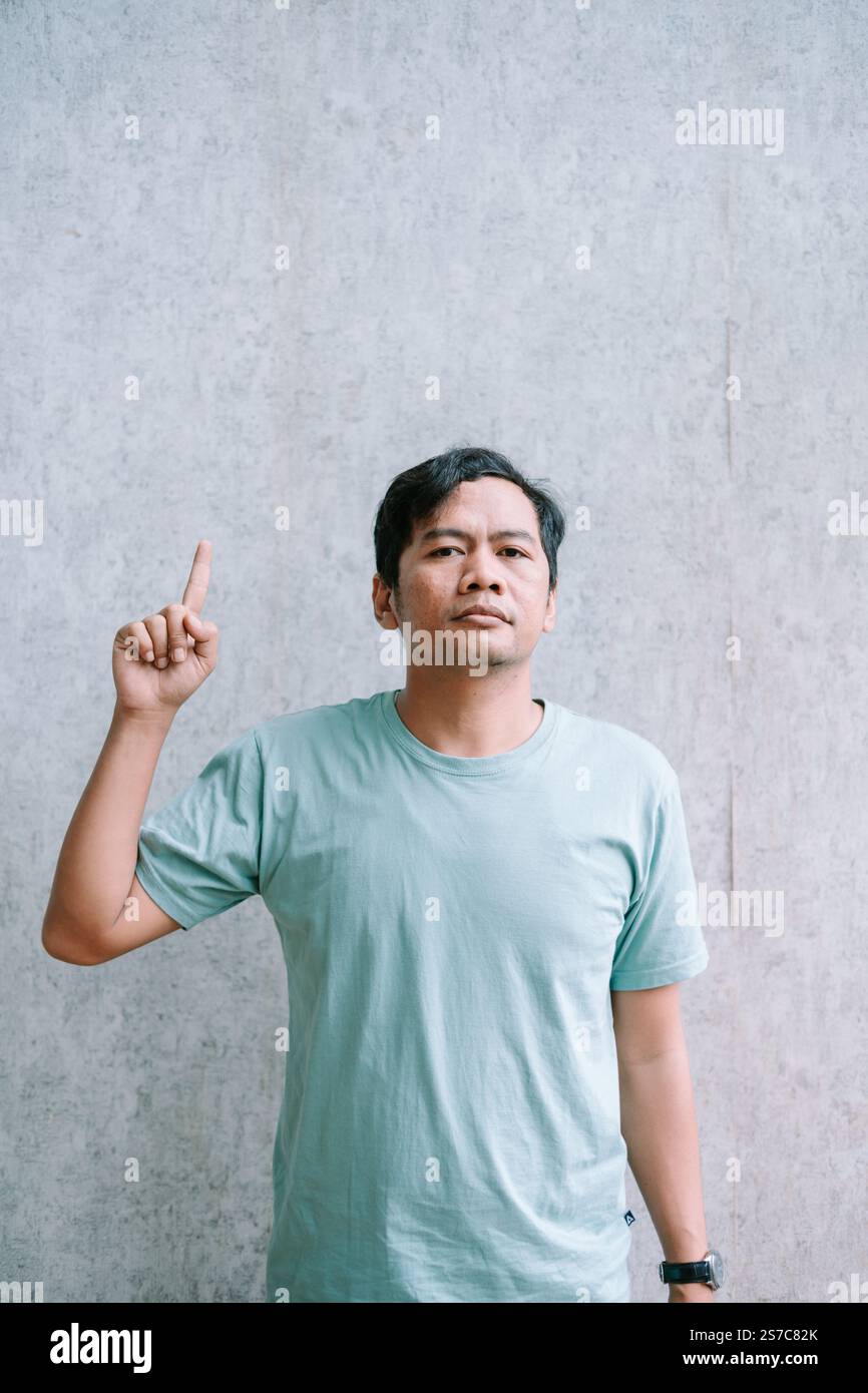 Uomo asiatico che punta verso l'alto, avendo un'idea brillante. Foto Stock