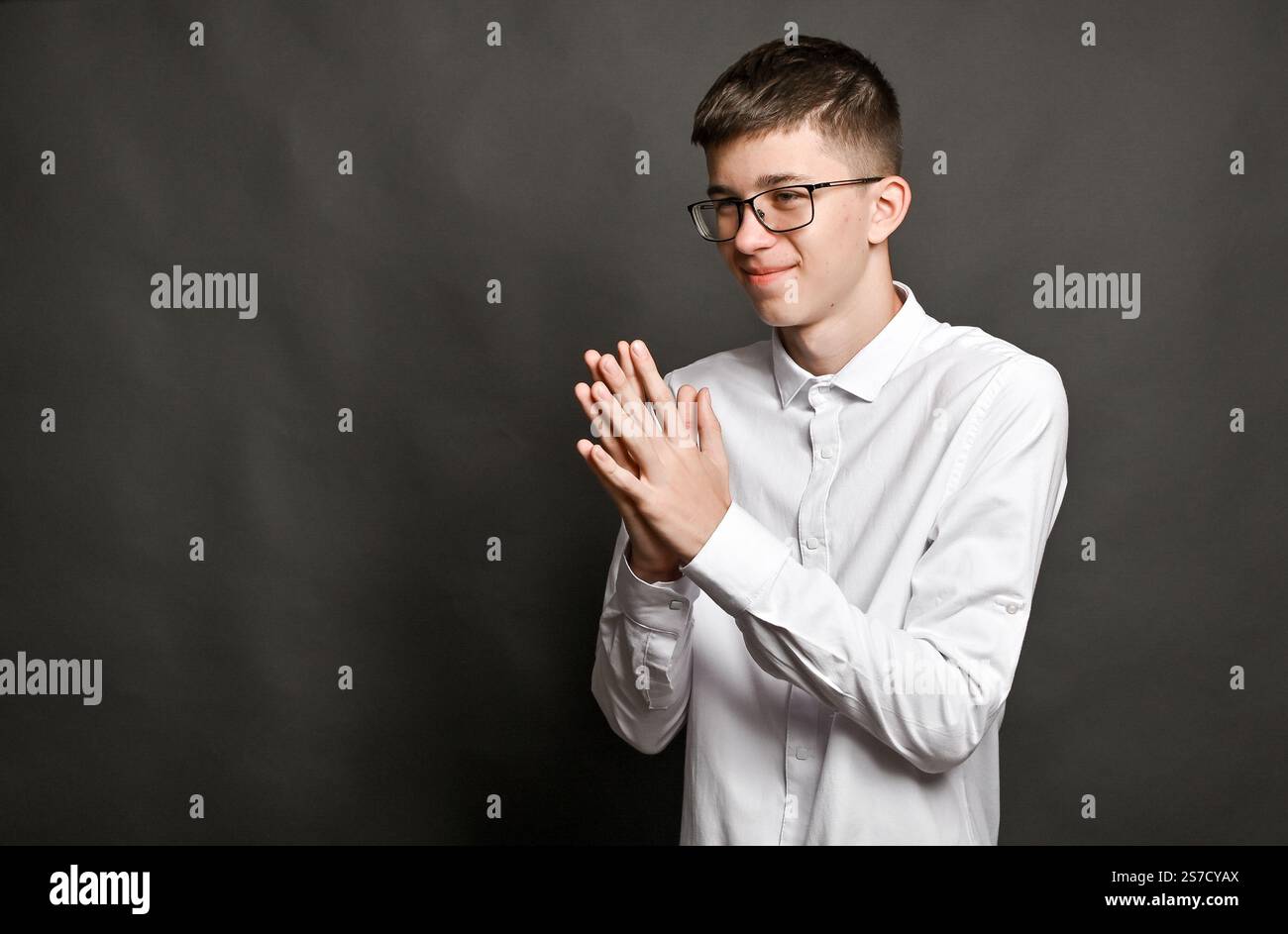 un ragazzo sorridente ha stretto i palmi insieme. un concetto su sfondo grigio Foto Stock