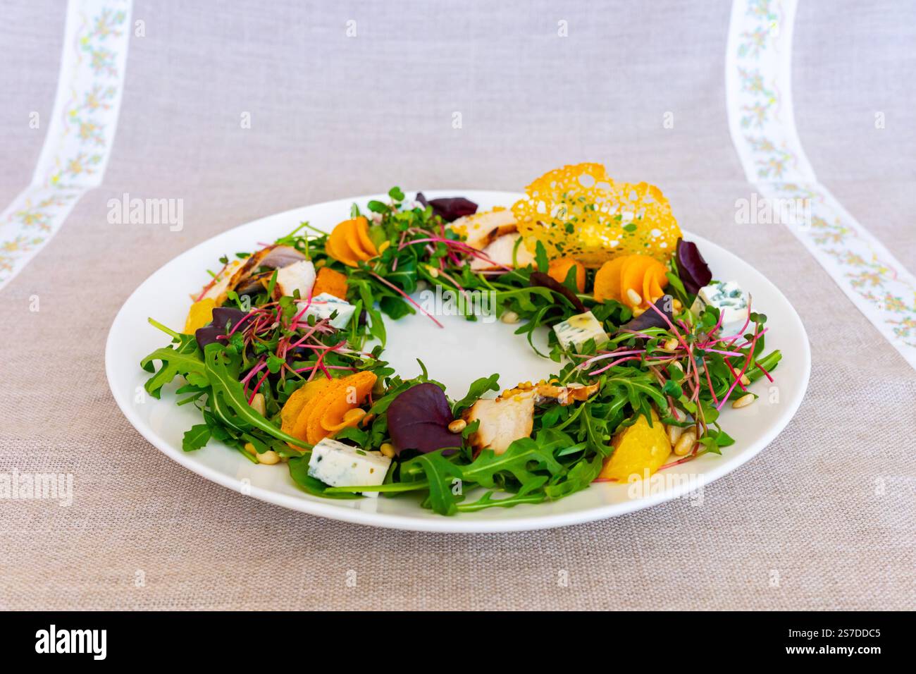 Un'insalata splendidamente allestita presenta verdure fresche, varie verdure colorate e condimenti decorativi su un piatto bianco, mettendo in risalto le arti culinarie Foto Stock