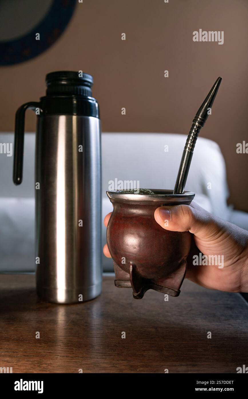 Mano che tiene un te' compagno, una bevanda calda. Foto Stock
