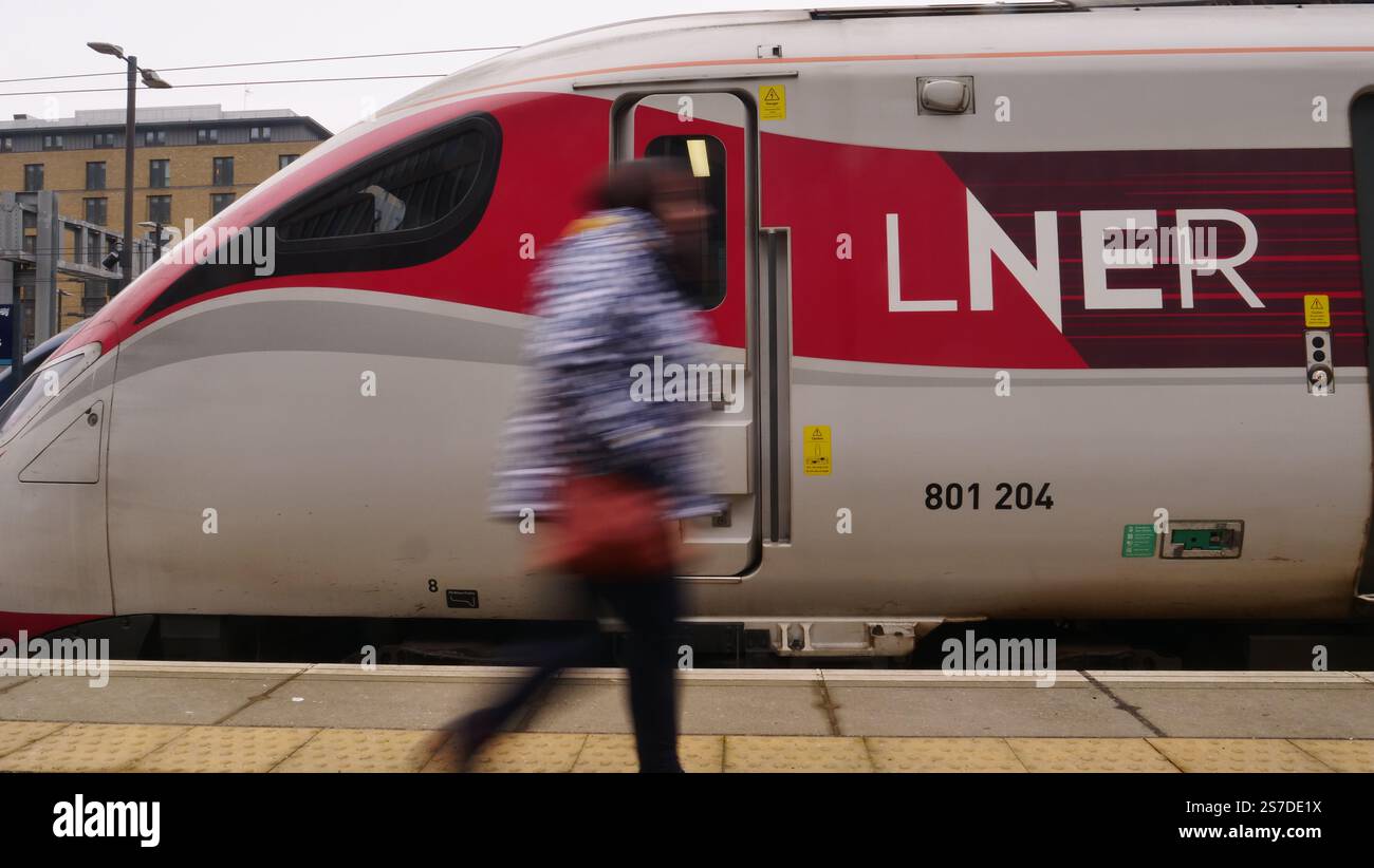 Un pendolare passa davanti a un treno LNER Azuma alla stazione di Kings Cross, Londra Foto Stock