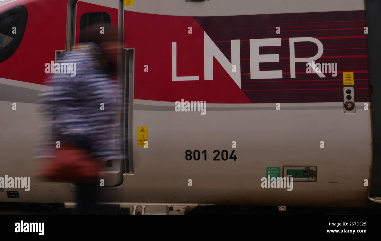 Un pendolare passa davanti a un treno LNER Azuma alla stazione di Kings Cross, Londra Foto Stock