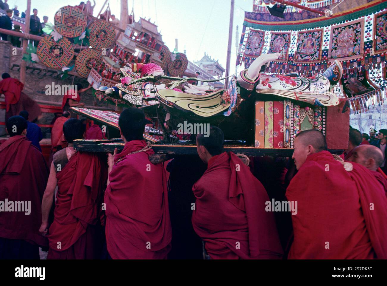 I monaci buddisti tibetani portano con sé una massiccia scultura religiosa realizzata con burro Yak durante il Festival della scultura del burro Yak presso il monastero di Kumbum, noto anche come monastero Ta'er, 12 febbraio 1990 a Lusar, Xining, Qinghai, Cina. Le sculture sono assemblate in un massiccio tableau e esposte nel corso dell'anno successivo. Foto Stock