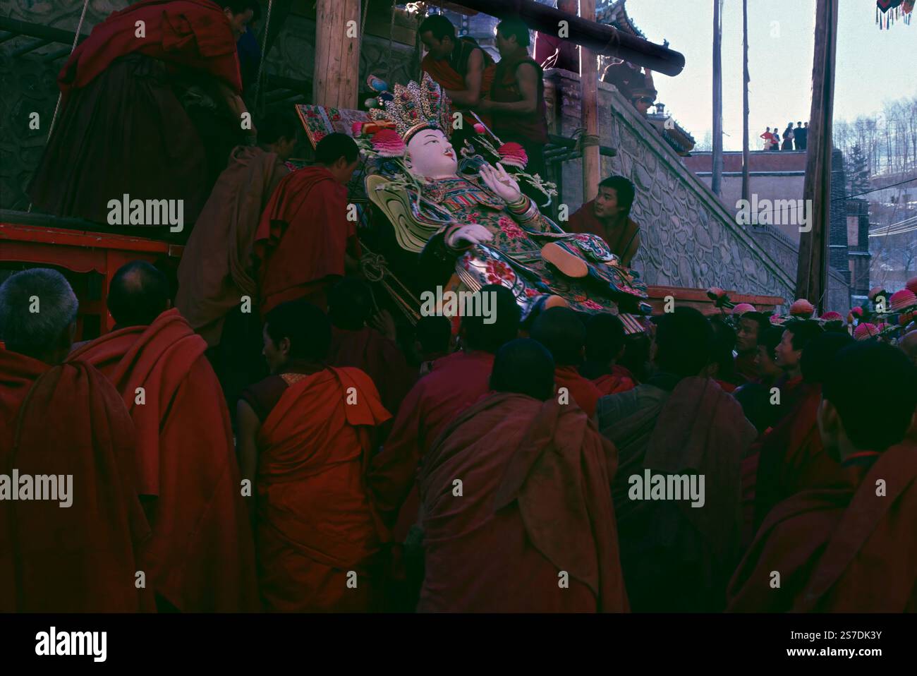 I monaci buddisti tibetani trasportano una massiccia scultura religiosa nelle prime ore del mattino durante il Festival della scultura del burro di Yak presso il monastero di Kumbum, noto anche come Monastero di Ta'er, 12 febbraio 1990 a Lusar, Xining, Qinghai, Cina. Le sculture sono assemblate in un massiccio tableau e esposte nel corso dell'anno successivo. Foto Stock