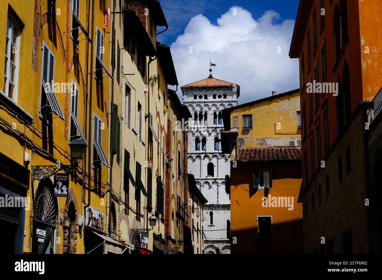 Via Beccheria, una via dello shopping nel centro storico di Lucca con alla fine il campanile medievale Foto Stock