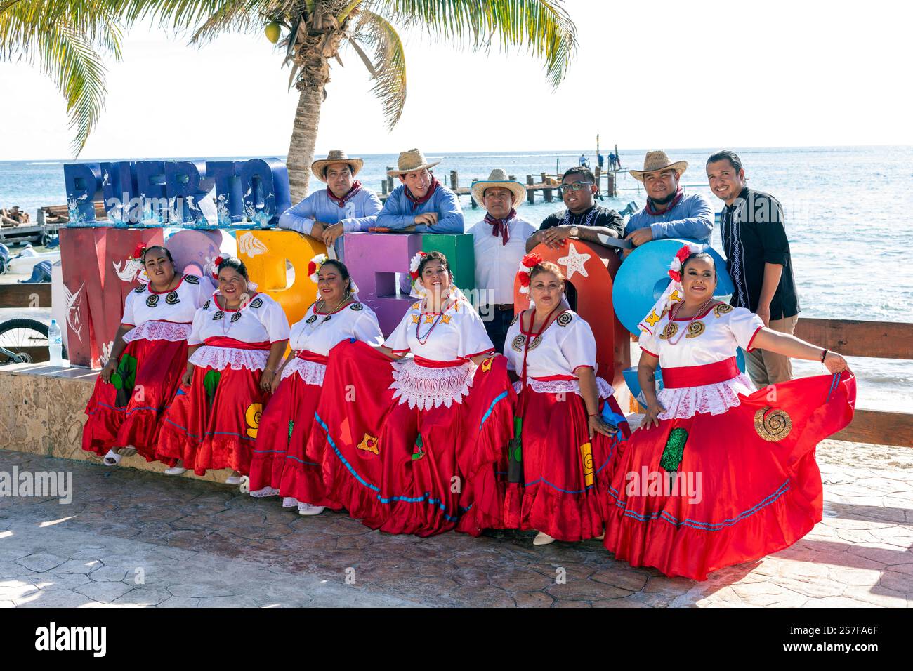 Messico, Puerto Morelos, un gruppo di donne ballerine in costume tradizionale che posano con un gruppo di uomini Foto Stock