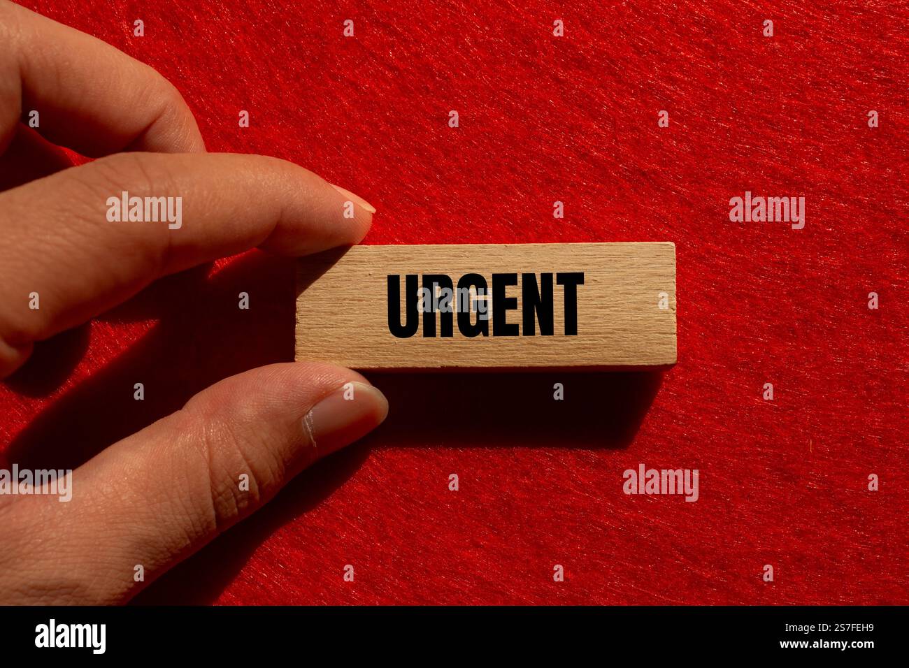 Messaggio urgente scritto su un blocco di legno con sfondo rosso. Simbolo di parola urgente concettuale. Copia spazio. Foto Stock