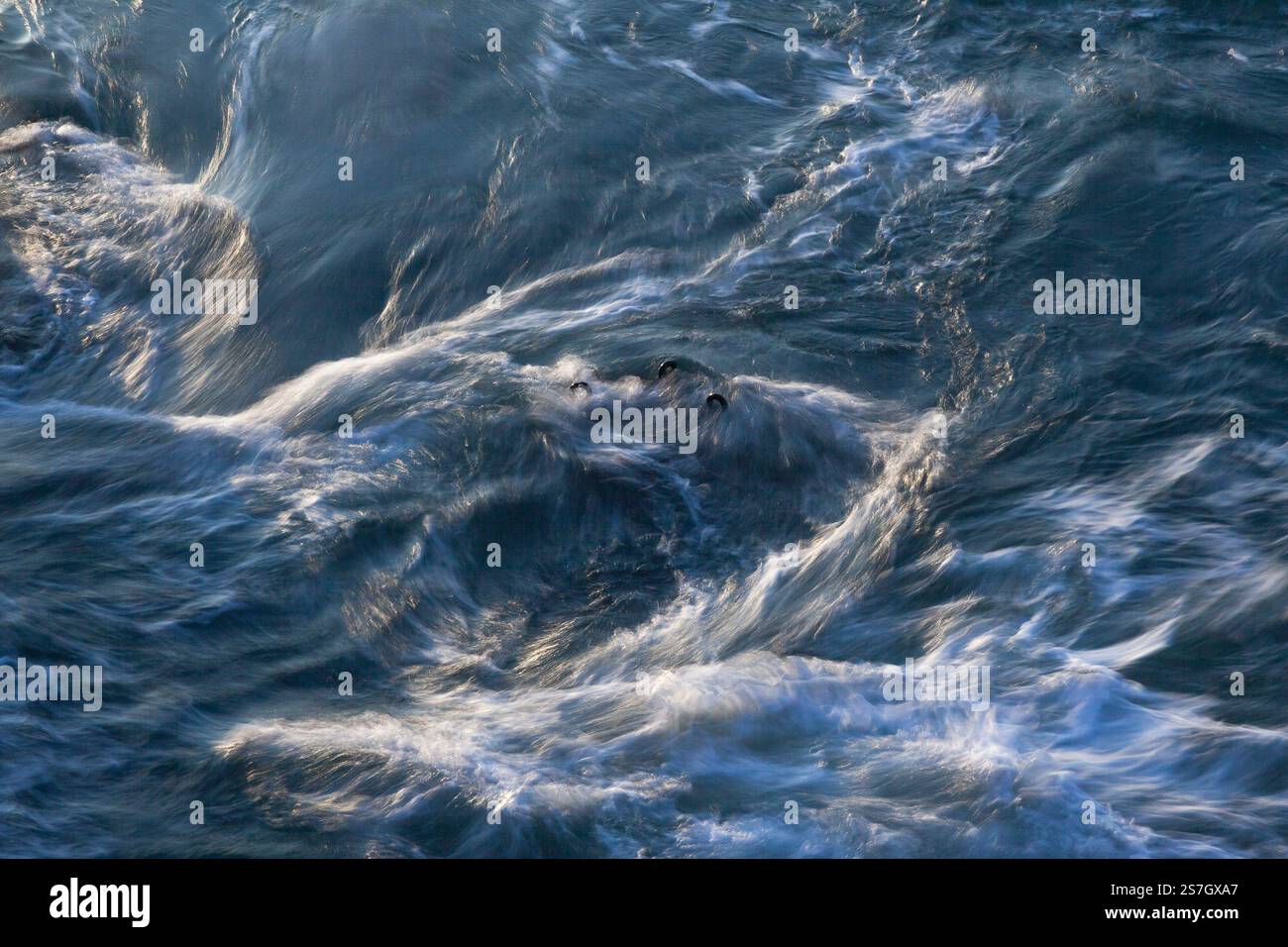 La bassa velocità dell'otturatore crea acqua vorticosa intorno ai ganci di ormeggio nell'oceano | Porthleven, Cornovaglia Foto Stock