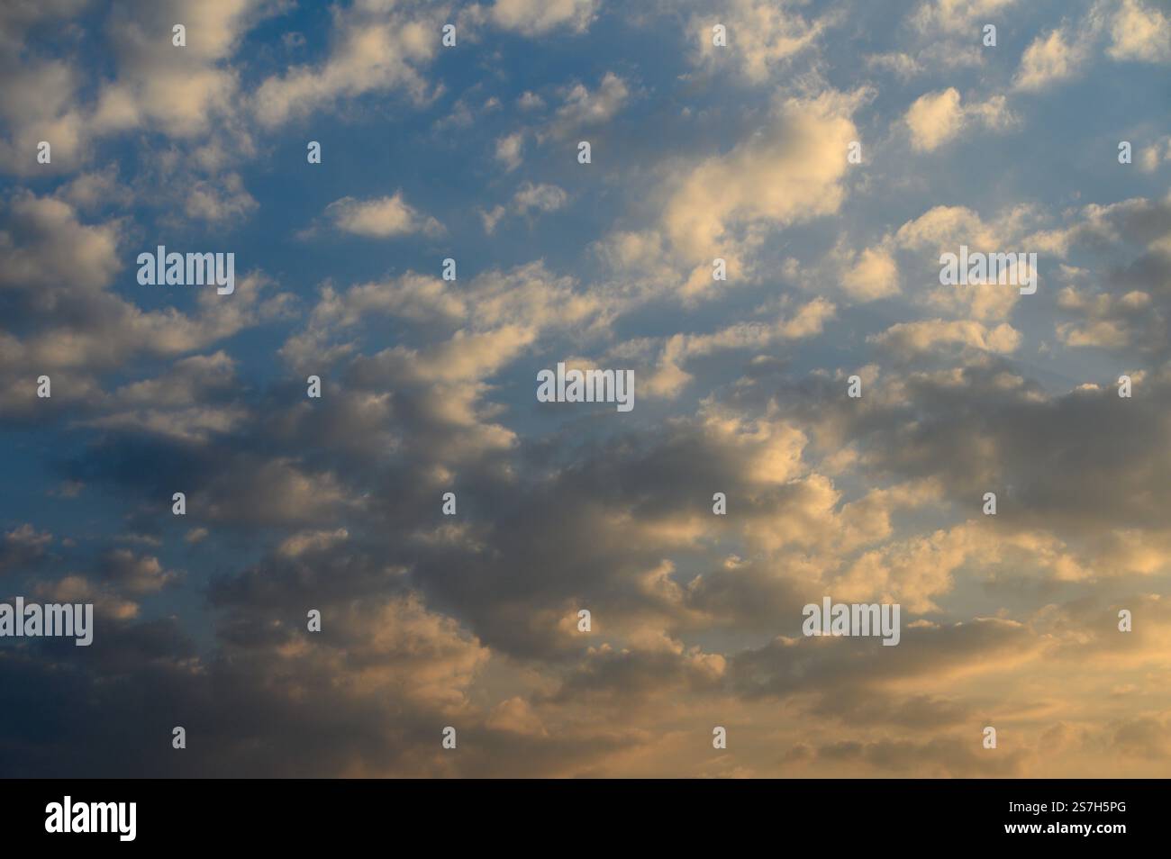 I colori si fondono al tramonto, proiettando un caldo bagliore su soffici nuvole che si spostano tranquillamente sopra l'orizzonte. Foto Stock