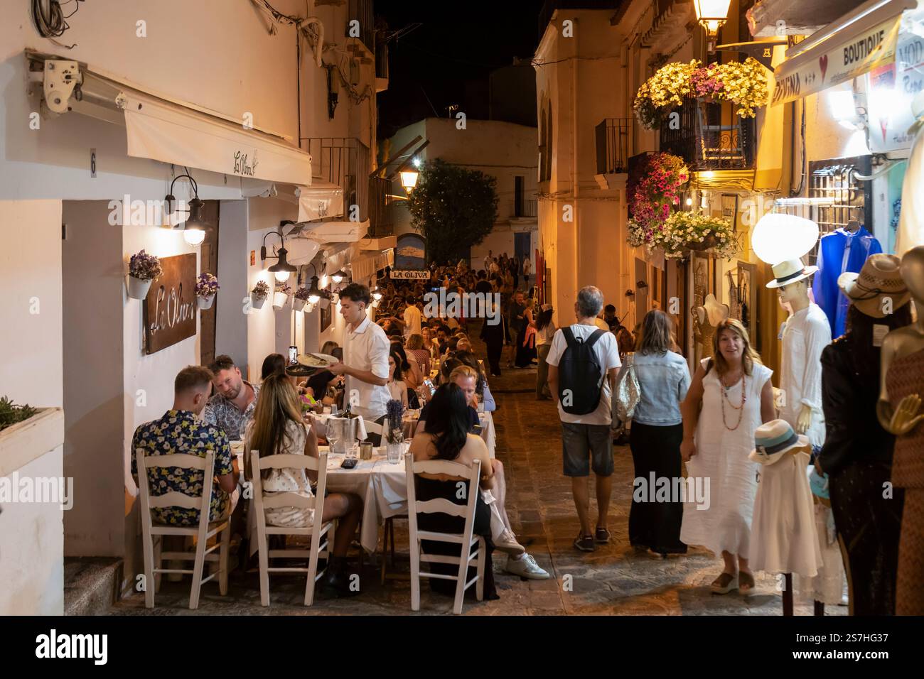 La gente cena fuori la sera su una stretta strada di Dalt Vila nella città vecchia di Ibiza. Foto Stock