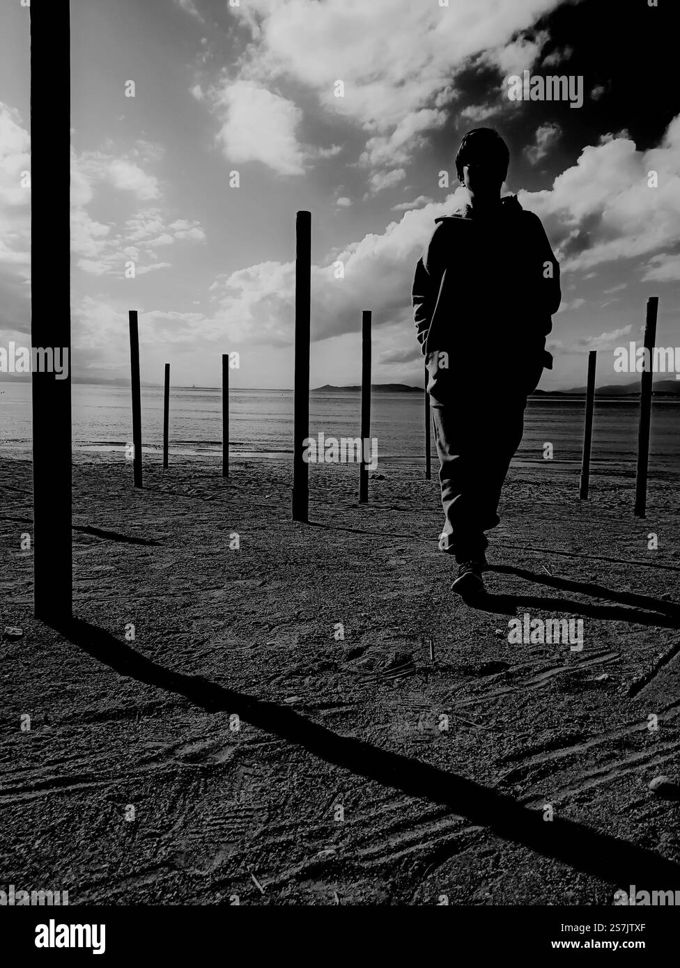 La foto in bianco e nero cattura una figura solitaria sagomata su uno sfondo costiero, Atene Grecia - 6 gennaio 2025 Foto Stock